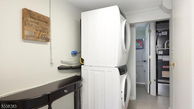 laundry area featuring laundry area, stacked washer and dryer, and light tile patterned floors