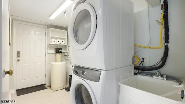 clothes washing area featuring stacked washer and dryer, laundry area, and a sink