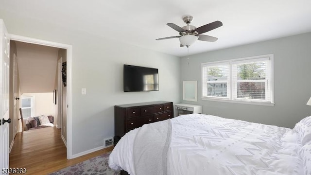 bedroom featuring baseboards, ceiling fan, wood finished floors, and visible vents