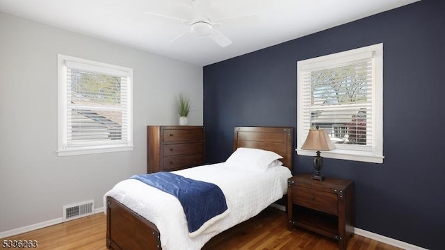 bedroom with ceiling fan, baseboards, visible vents, and wood finished floors