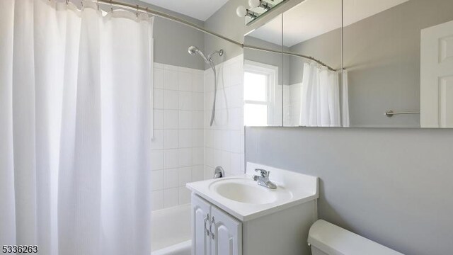 bathroom with toilet, shower / bath combination with curtain, and vanity