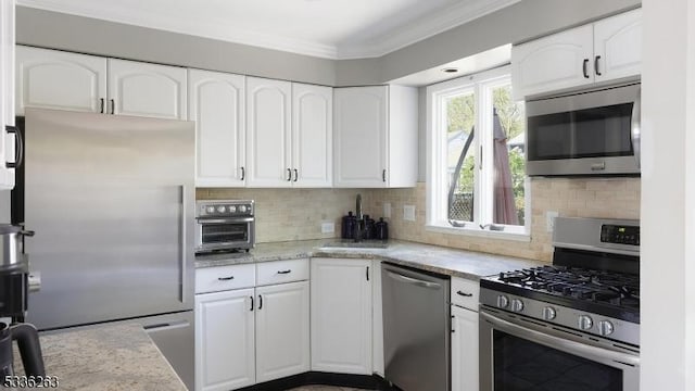 kitchen featuring white cabinets, stainless steel appliances, ornamental molding, and tasteful backsplash