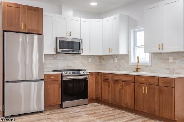 kitchen featuring backsplash, appliances with stainless steel finishes, light hardwood / wood-style floors, and white cabinets