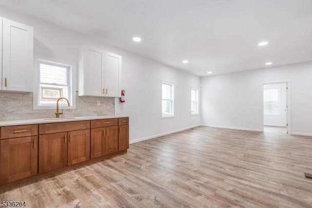 kitchen with white cabinetry, sink, tasteful backsplash, and light wood-type flooring