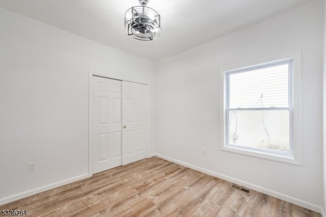 unfurnished bedroom with light wood-type flooring and a closet