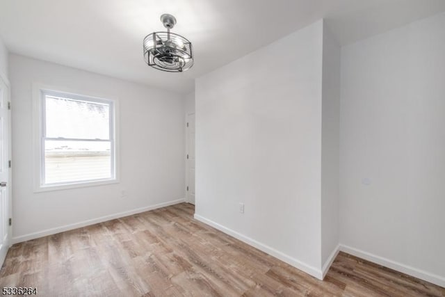 empty room with a chandelier and light wood-type flooring