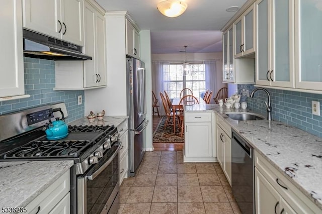 kitchen with light tile patterned flooring, tasteful backsplash, sink, hanging light fixtures, and stainless steel appliances