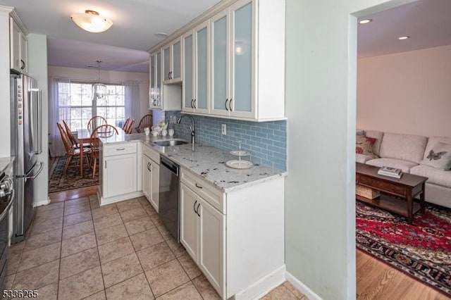 kitchen with sink, appliances with stainless steel finishes, tasteful backsplash, decorative light fixtures, and kitchen peninsula