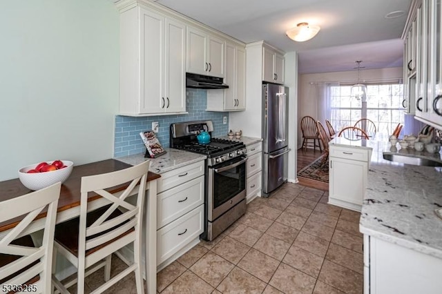 kitchen featuring appliances with stainless steel finishes, pendant lighting, tasteful backsplash, sink, and light stone counters