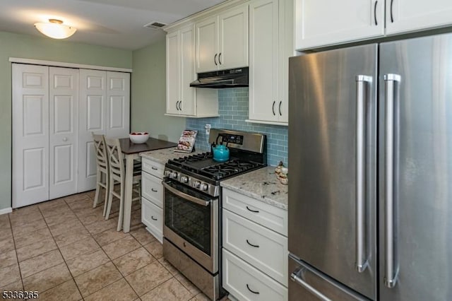 kitchen with stainless steel appliances, light stone countertops, light tile patterned floors, and backsplash