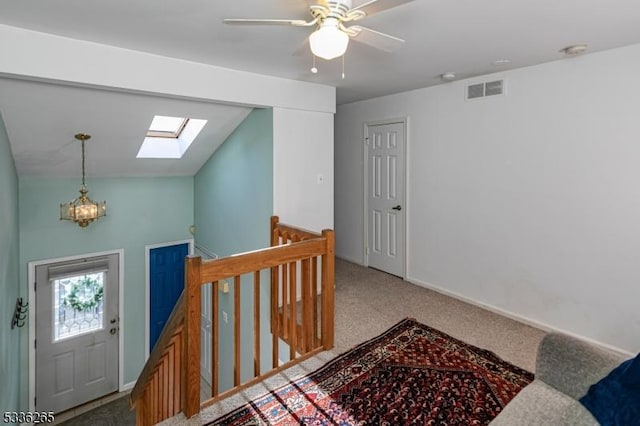 interior space featuring an inviting chandelier, vaulted ceiling with skylight, and carpet floors