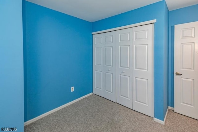 unfurnished bedroom featuring light colored carpet and a closet