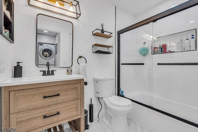 full bathroom featuring vanity, toilet, stacked washer and clothes dryer, and combined bath / shower with glass door