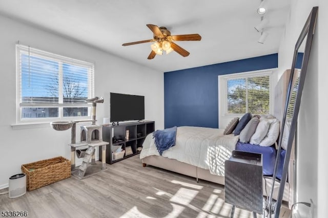 bedroom with rail lighting, hardwood / wood-style floors, and ceiling fan