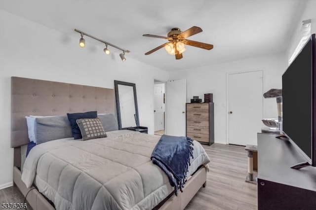 bedroom featuring rail lighting, ceiling fan, and light hardwood / wood-style flooring