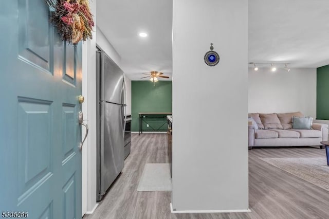 corridor with light hardwood / wood-style flooring and rail lighting