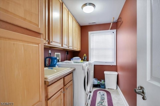 washroom featuring separate washer and dryer, sink, light tile patterned floors, and cabinets