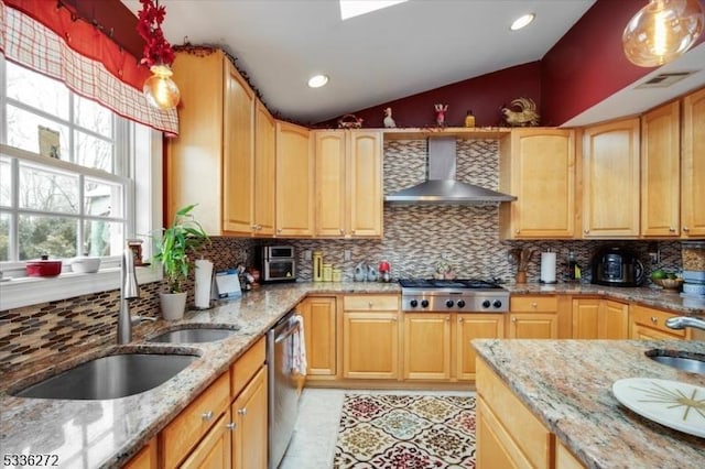 kitchen with lofted ceiling, sink, light stone counters, appliances with stainless steel finishes, and wall chimney range hood