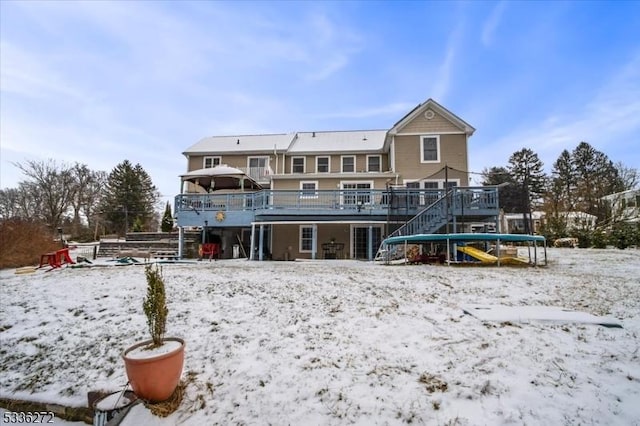 snow covered rear of property with a deck