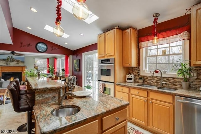 kitchen with light stone counters, sink, pendant lighting, and appliances with stainless steel finishes