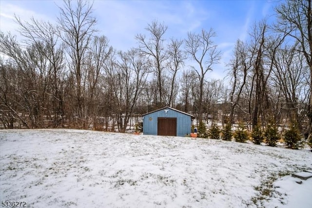 yard layered in snow with a garage and an outdoor structure