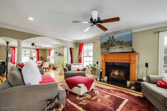 living room featuring decorative columns, ornamental molding, wood-type flooring, and ceiling fan