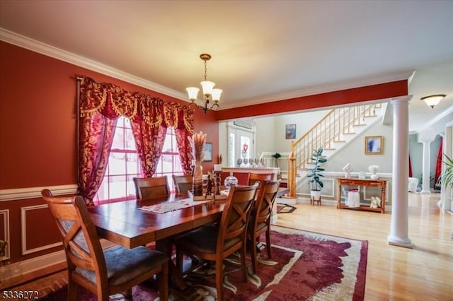 dining space with ornate columns, crown molding, light wood-type flooring, and a chandelier