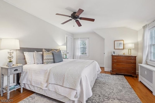 bedroom featuring hardwood / wood-style flooring, ceiling fan, vaulted ceiling, and radiator