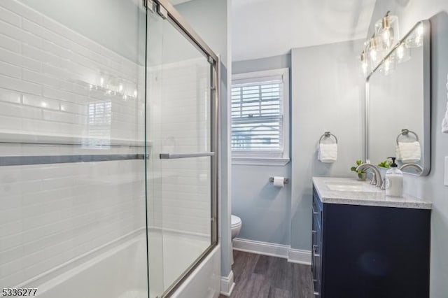 full bathroom featuring toilet, vanity, bath / shower combo with glass door, and wood-type flooring