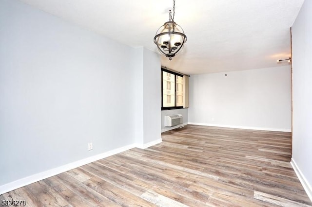 unfurnished living room featuring hardwood / wood-style flooring, a wall mounted AC, and an inviting chandelier