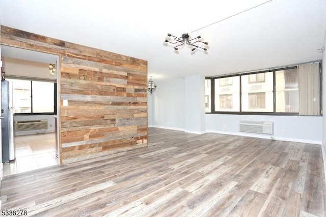 unfurnished living room with a wall mounted air conditioner and hardwood / wood-style floors