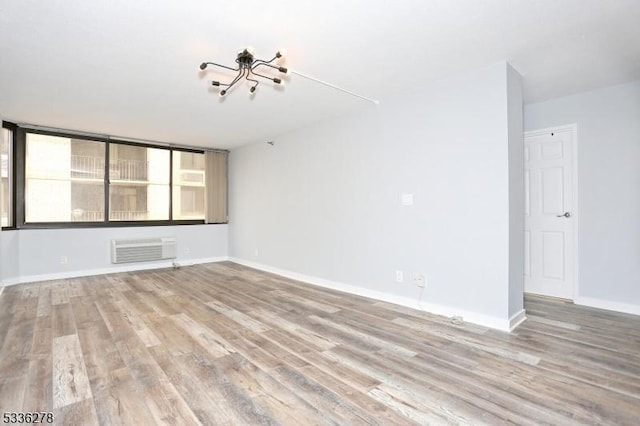 spare room with a wall mounted AC and light hardwood / wood-style floors