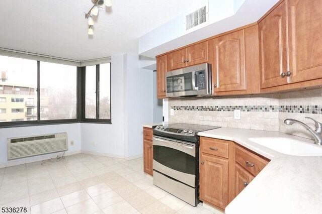 kitchen featuring tasteful backsplash, sink, an AC wall unit, and appliances with stainless steel finishes