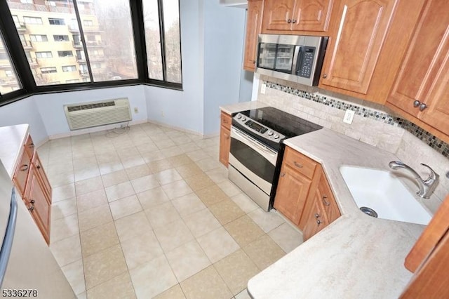 kitchen featuring appliances with stainless steel finishes, tasteful backsplash, sink, light tile patterned floors, and a wall unit AC