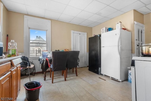 kitchen featuring a paneled ceiling, black fridge, and white refrigerator