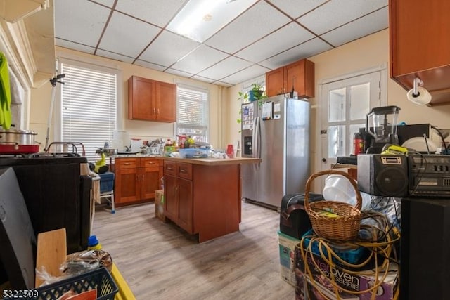 kitchen featuring light wood-type flooring, a center island, stainless steel fridge with ice dispenser, and a drop ceiling