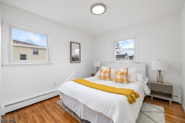 bedroom with a baseboard heating unit and light hardwood / wood-style flooring