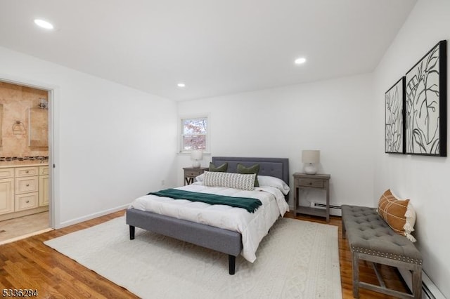 bedroom featuring a baseboard radiator, ensuite bathroom, and light wood-type flooring