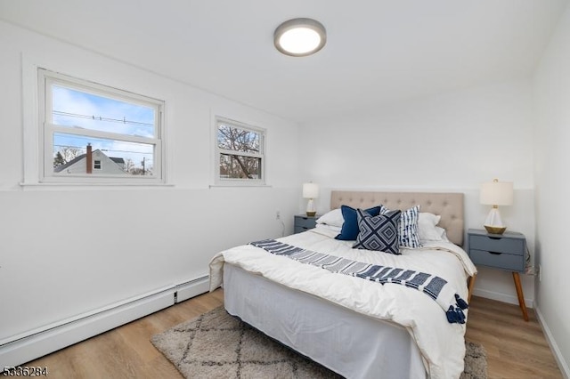 bedroom with a baseboard heating unit and light hardwood / wood-style flooring