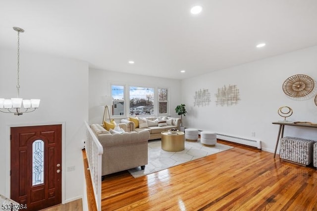 living room with baseboard heating, a chandelier, and hardwood / wood-style flooring