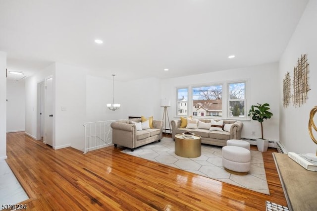 living room with an inviting chandelier, a baseboard radiator, and light hardwood / wood-style floors