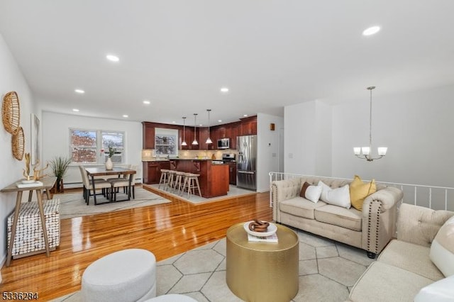 living room with an inviting chandelier, light hardwood / wood-style flooring, and a baseboard heating unit