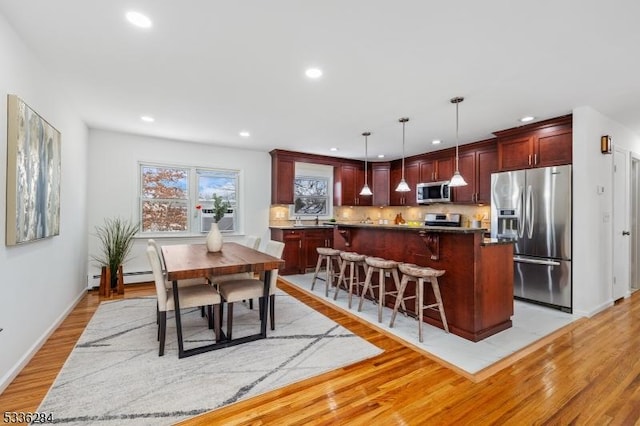 kitchen featuring decorative light fixtures, stainless steel appliances, a center island, and a kitchen bar