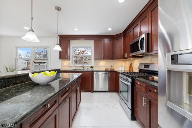 kitchen with sink, appliances with stainless steel finishes, hanging light fixtures, backsplash, and dark stone counters