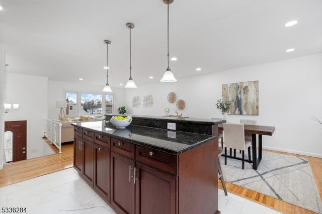 kitchen with a breakfast bar, dark stone counters, decorative light fixtures, and a center island