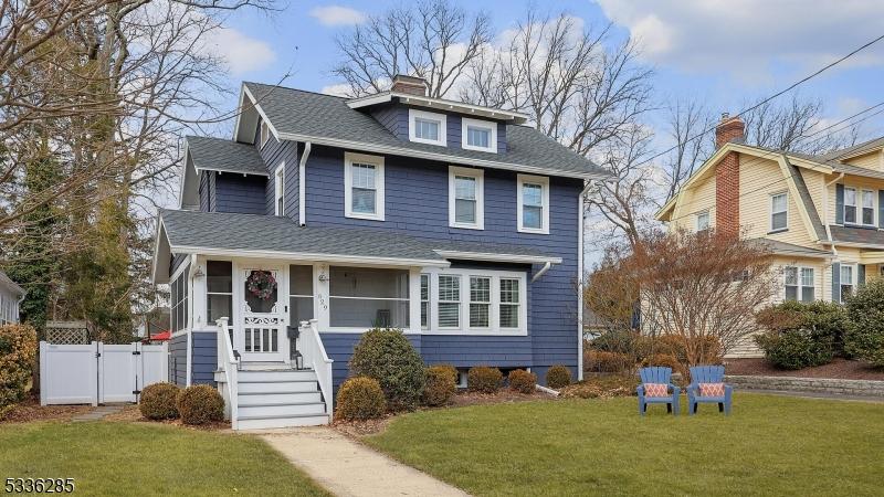 traditional style home featuring a shingled roof, a sunroom, a gate, fence, and a front lawn