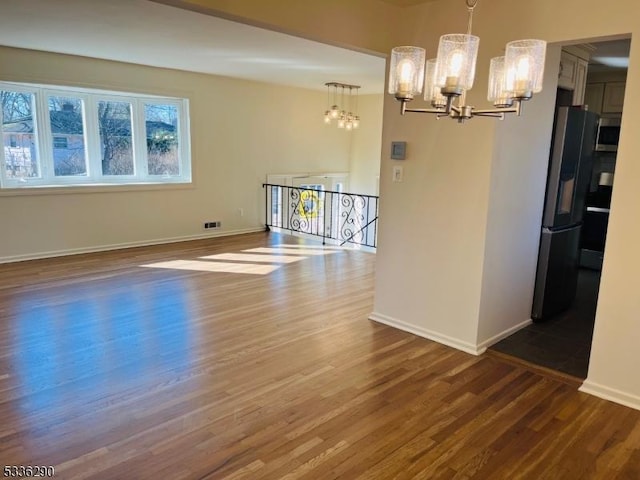 interior space with baseboards, wood finished floors, visible vents, and an inviting chandelier