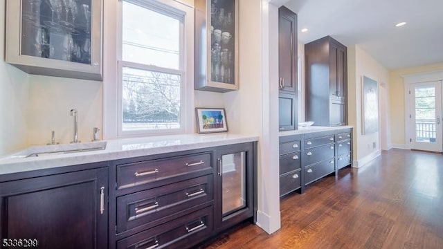 bar featuring dark wood-style floors, recessed lighting, a sink, and baseboards