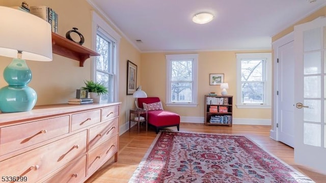 living area with baseboards, visible vents, light wood-style flooring, and crown molding