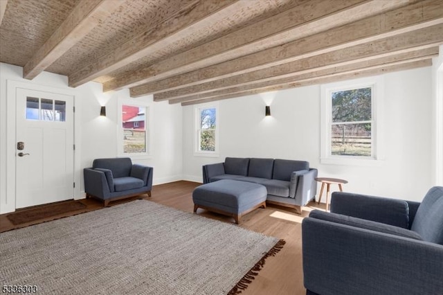 living area featuring beam ceiling, baseboards, and wood finished floors